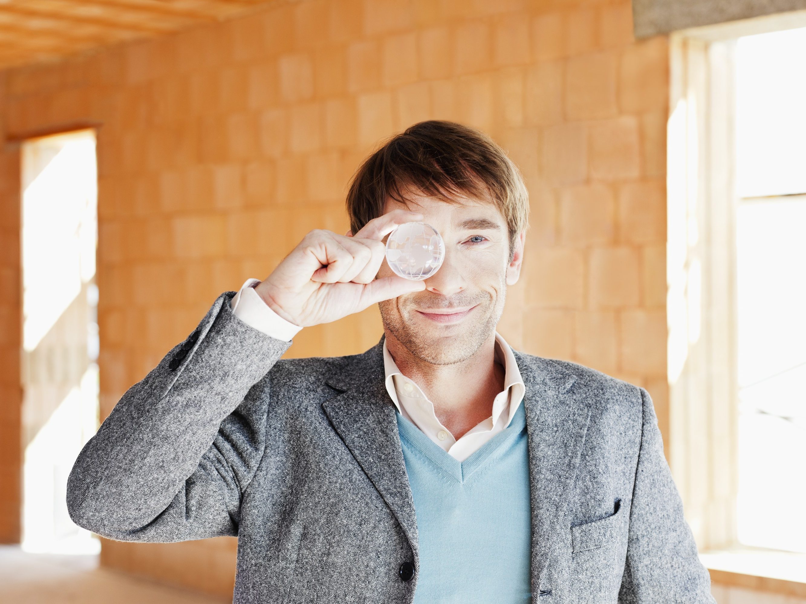 Smiling man looking through a glass globe facing camera
