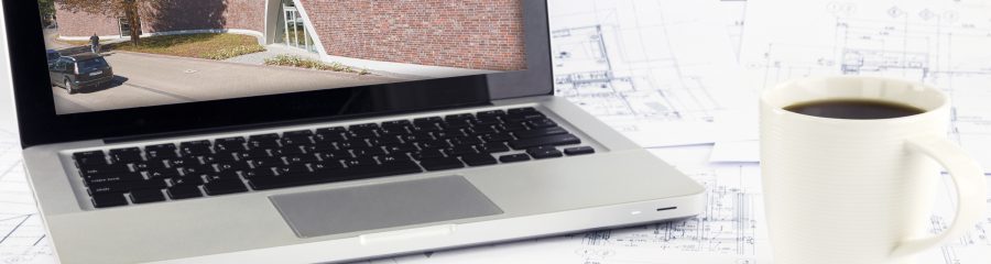 Working space with reference picture on laptop and architecture plan on desk