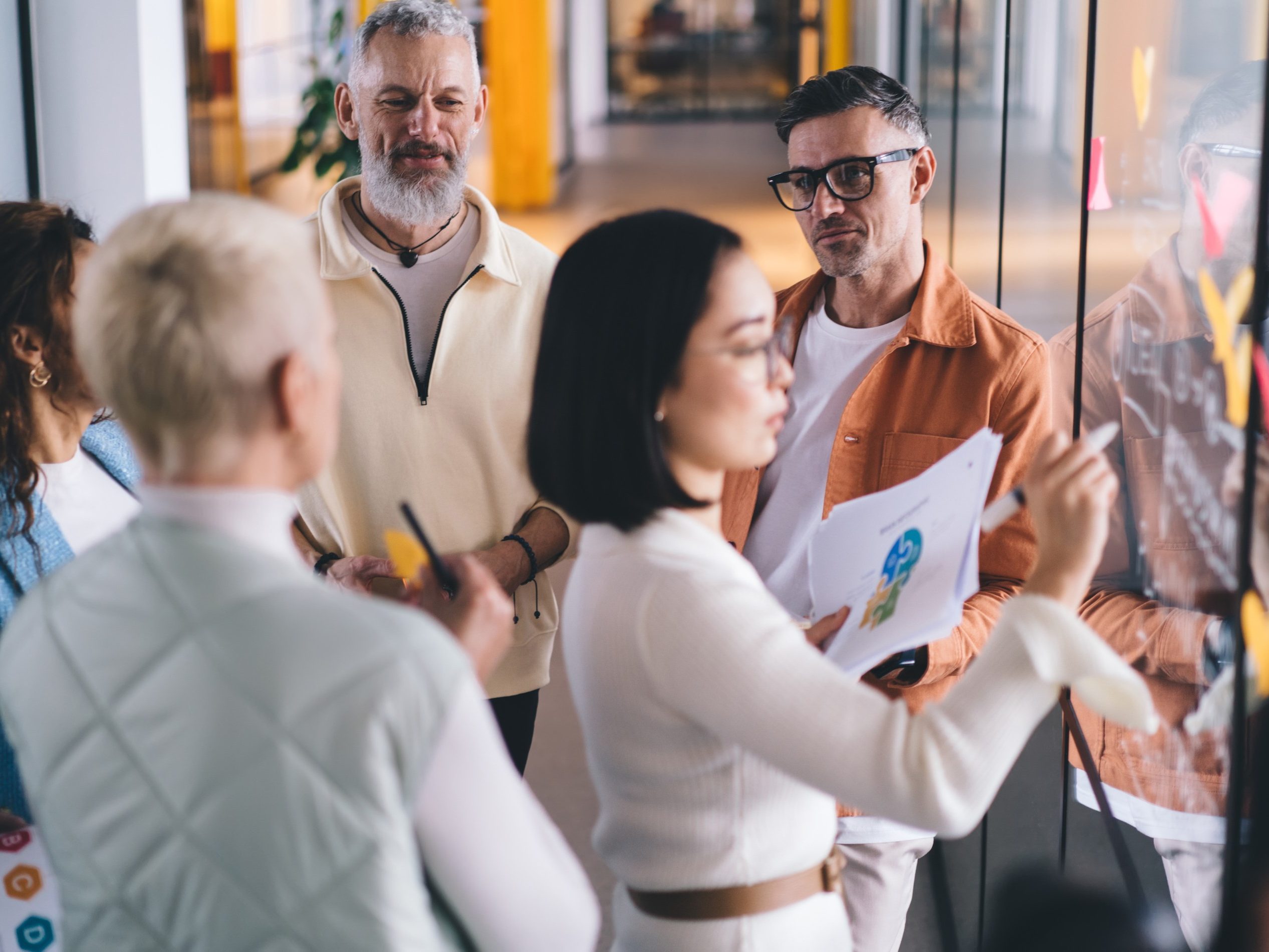 From above of team of coworkers sharing and analyzing ideas with executive manager and creating business project while cooperating in modern workspace