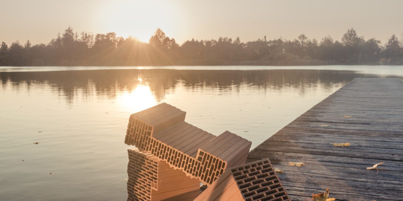 Photo with bricks Porotherm EKO+ Profi  in nature in the background of the pond and coming sun