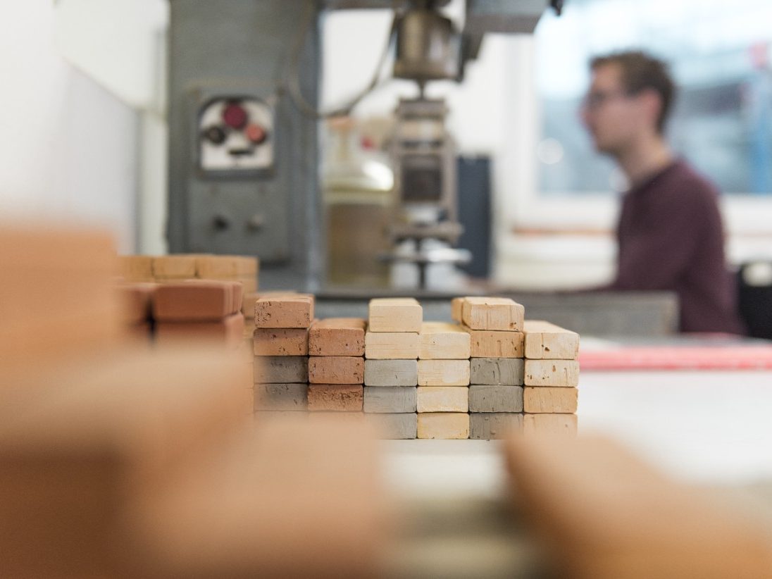 Worker in laboratory with clay samples in foreground