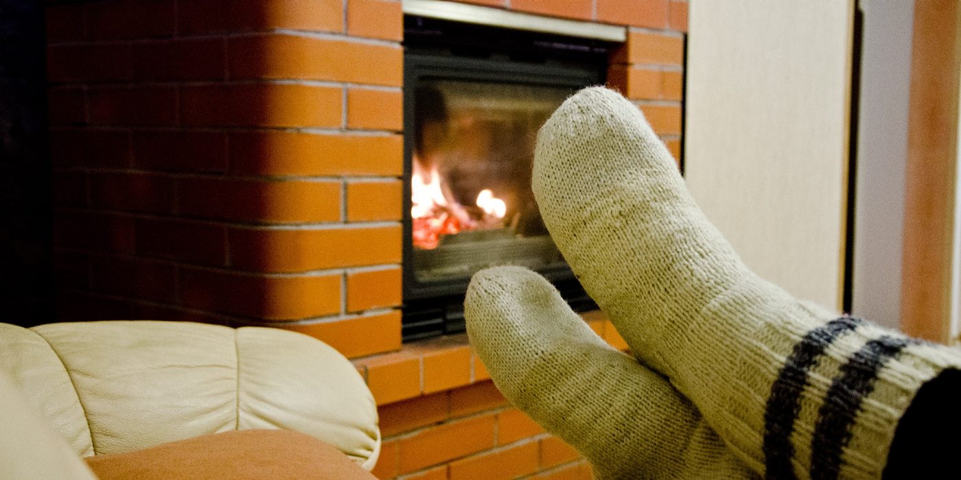 Someone sitting in the front of fireplace.